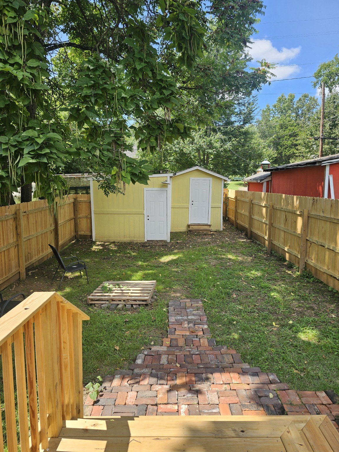 Fully fenced backyard with brick path and two-door detached outbuilding