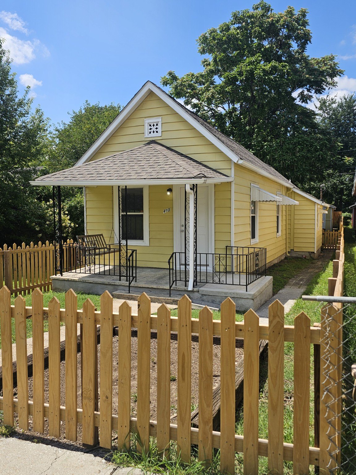 Yellow cottage at 413 E Anderson Avenue with covered front porch and new picket fence
