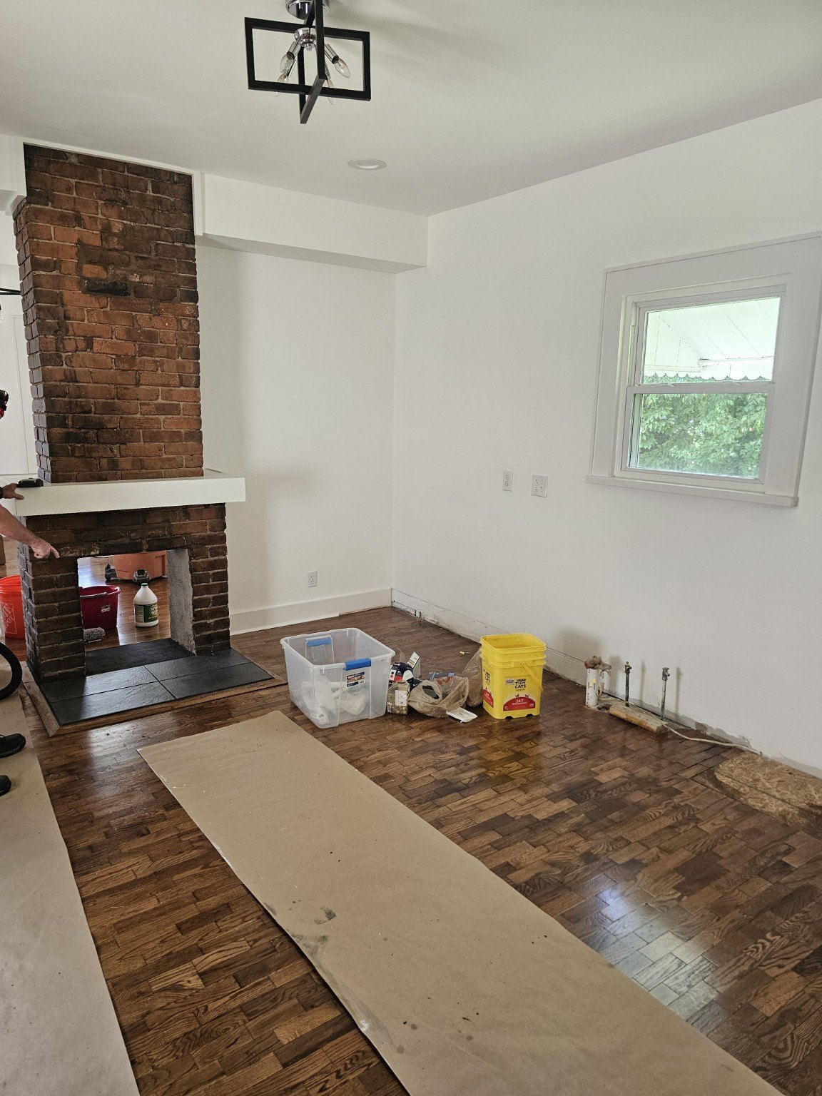 Living room with refinished hardwood floor and exposed brick fireplace